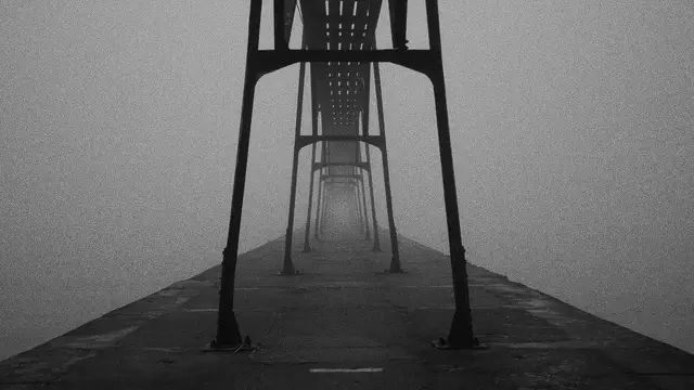 A seaside pier stretching away into thick fog